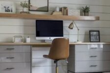 a modern country home office with a white planked wall, a grey desk, a leather chair, wooden slab floating shelves