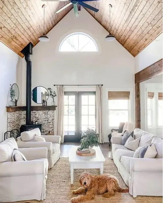 a modern country living room with a hearth, neutral furniture, a highlit slanted ceiling, printed and neutral textiles