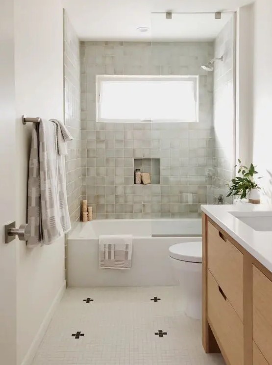 a modern farmhouse bathroom with a window, grey tiles, a tub, a tiled floor, a timber vanity and potted plants