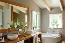 a modern farmhouse bathroom with an attic ceiling, a corner tub, a stained wall-mounted vanity, a mirror and some windows