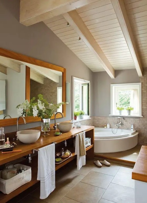 a modern farmhouse bathroom with an attic ceiling, a corner tub, a stained wall mounted vanity, a mirror and some windows