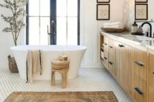 a modern farmhouse bathroom with paneled walls, a hex tile floor, a timber vanity, a tub, a mirror and shutters, wooden stools