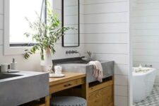 a modern farmhouse bathroom with shiplap walls, a geo tile floor, a stained timber vanity with concrete sinks, mirrors and black sconces