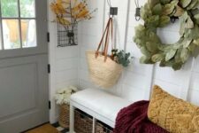 a modern farmhouse entryway with a built-in upholstered bench, a rack, some sings, greenery and leaves