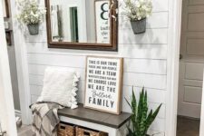 a modern farmhouse entryway with a shiplap wall, a wooden bench and baskets, a mirror, potted plants and lunaria arrangements