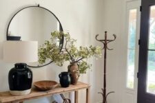 a modern farmhouse entryway with a stained console table, a couple of baskets, some lovely vases, a mirror and a rack