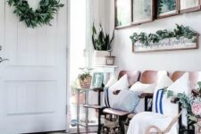 a modern farmhouse entryway with an arrangement of mirrors, a bench with pillows and blankets, potted greenery and a wreath