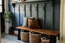 a modern farmhouse hallway with a black paneled wall, a bench, some baskets, potted greenery and blooms and round mirrors