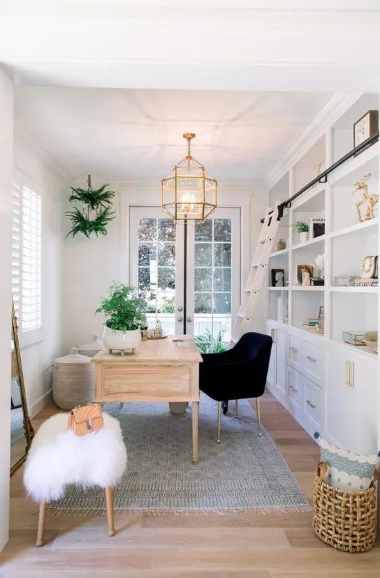 a modern farmhouse home office with a large white storage unit, a stained desk, a black chair, a fluffy stool and some potted greenery