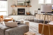 a modern farmhouse living room with a built-in fireplace, a grey sofa, a TV and a TV unit, a leather sofa and some stools
