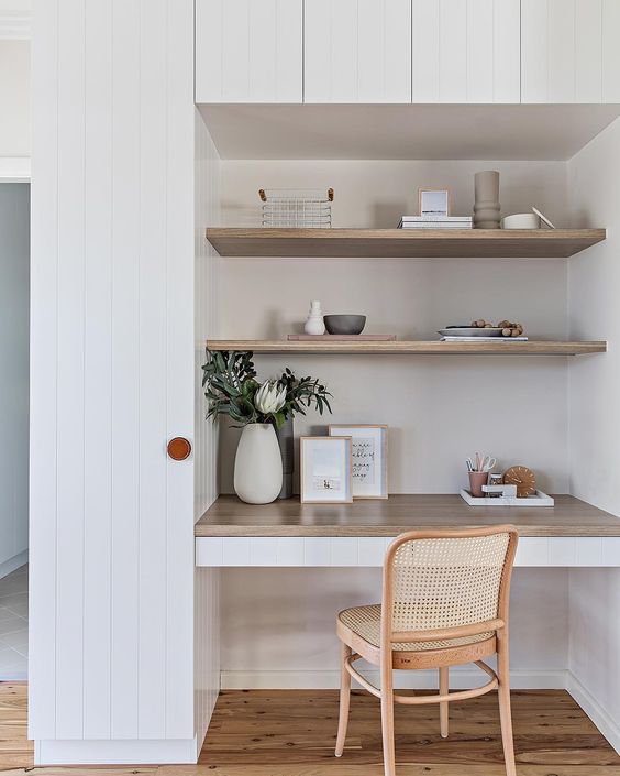 a modern niche with built-in shelves and a desk, some greenery and necessary stuff plus a rattan chair