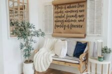 a modern rustic entryway with a wooden bench and pillows, candle lanterns and a sign, a potted plant and a framed mirror