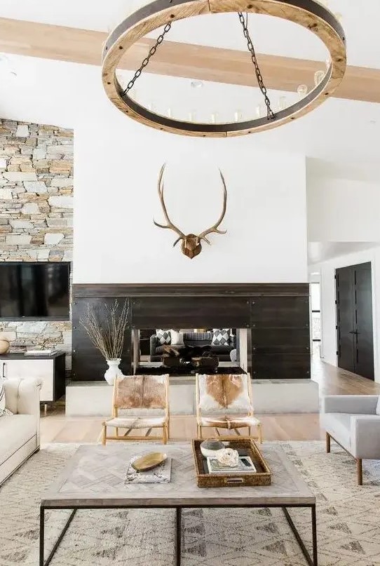 a modern rustic living room with jute, fur, wood and stone in decor plus cowhide chairs takes the best from two styles