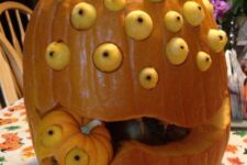 a multi-eyed pumpkin monster with a little pumpkin being eaten by it is a cool and bold idea for Halloween
