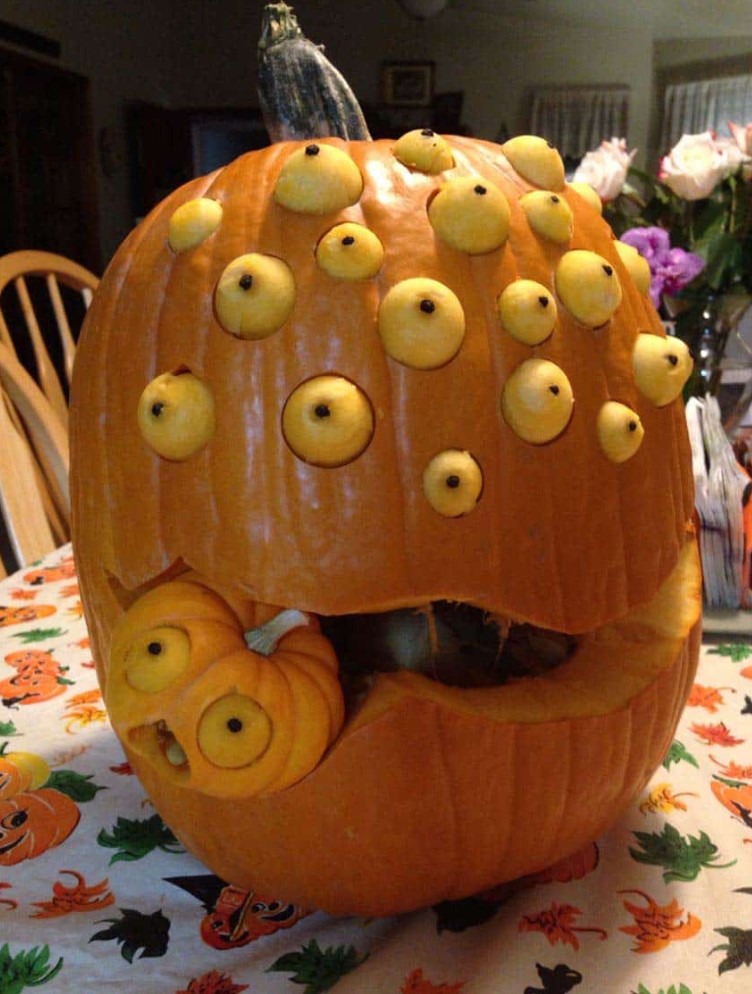 a multi-eyed pumpkin monster with a little pumpkin being eaten by it is a cool and bold idea for Halloween