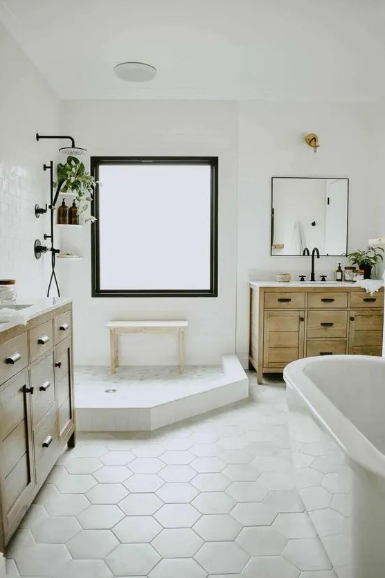 a neutral modern farmhouse bathroom with a shower space and a tub, a hex tile floor, timber vanitites, potted greenery and black hardware