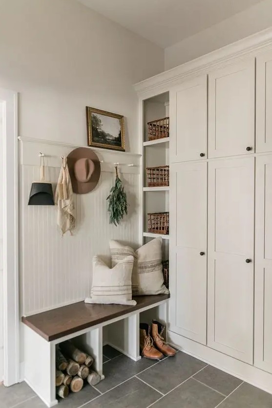 a neutral modern farmhouse entryway with a large storage unit, a built-in bench, some baskets and a rack