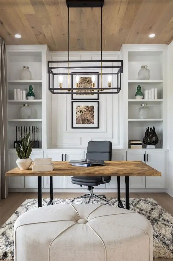 a neutral modern farmhouse home office with a large storage unit, a lightweight desk, a black chair and a neutral pouf, a frame chandelier