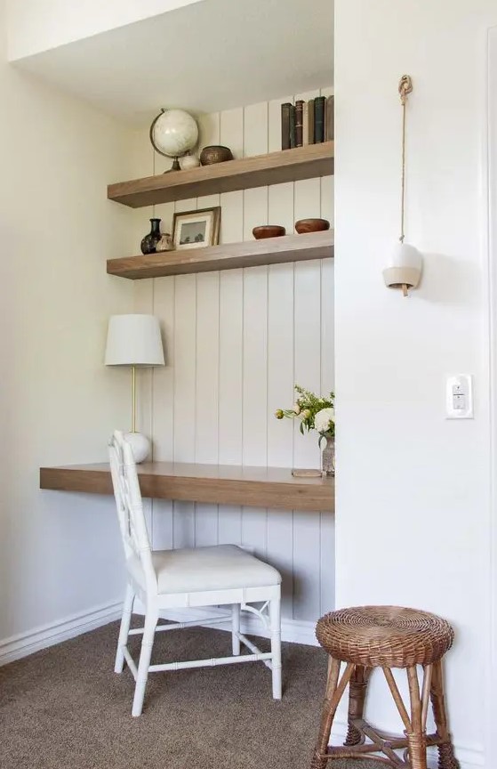 a neutral niche clad with white shiplap, stained shelves and a desk, books, vintage decor and vases, a table lamp