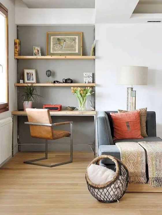 a niche painted grey, with built in shelves and a desk, some lovely decor, artwork, greenery and blooms and a comfy leather chair