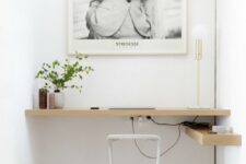 a niche with a built-in shelf-like desk, a small shelf, an artwork, greenery and decor is a cool home office nook to rock