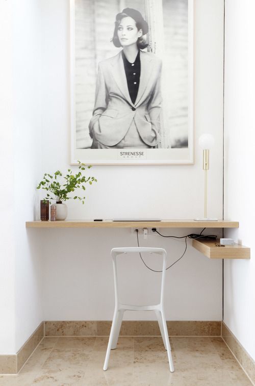a niche with a built-in shelf-like desk, a small shelf, an artwork, greenery and decor is a cool home office nook to rock