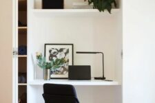 a niche with a small home office, a built-in shelf and a desk, a black chair, some decor and a stylish table lamp