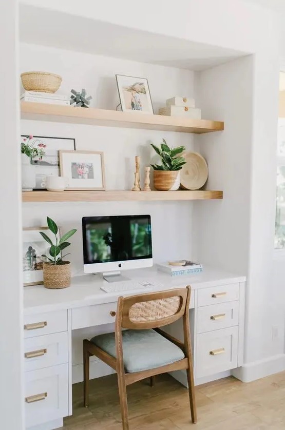 a niche with built-in shelves and a desk with storage drawers, with decor, potted greenery and a comfy chair