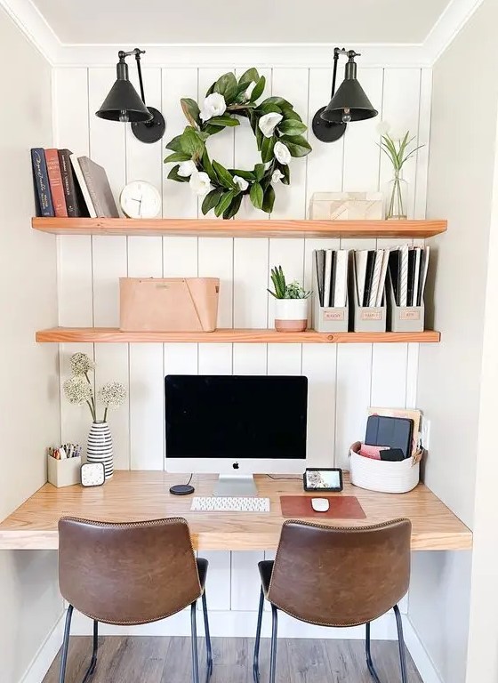 a niche with shiplap, built in shelves, a desk, potted greenery, black sconces, books and brown leather chairs