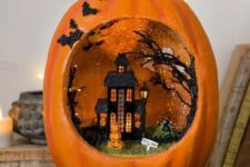 a pretty orange pumpkin diorama with a black house and trees, a stack of pumpkins and grass plus glitter bats on one side