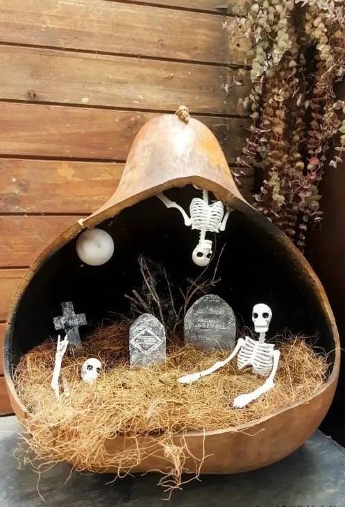 a pumpkin diorama with hay, a graveyard, skeletons and skulls and a moon is a unique solution that will catch an eye