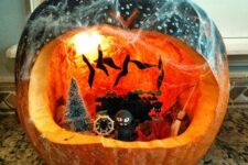 a pumpkin terrarium with bats, a tree, some ghosts and monsters, lights and some spiderweb on top