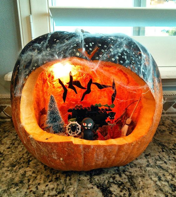 a pumpkin terrarium with bats, a tree, some ghosts and monsters, lights and some spiderweb on top