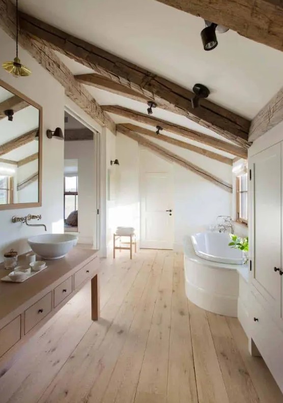 a refined modern farmhouse bathroom with a timber table vanity, wooden beams on the ceiling, a tub, a large wardrobe