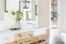 a refined modern farmhouse bathroom with an oval tub, built-in shelves, a double timber vanity with a marble countertop, mirrors and sconces