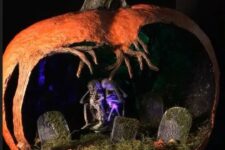 a scary Halloween diorama with moss, a graveyard, skeletons, purple lights and a crazily cutout pumpkin