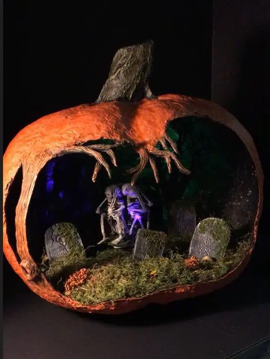 a scary Halloween diorama with moss, a graveyard, skeletons, purple lights and a crazily cutout pumpkin