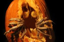 a scary carved Halloween pumpkin with eyes, teeth and monster hands is a bold and cool idea for Halloween