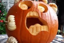 a scary carved pumpkin being eaten by other mini pumpkins is a very fun and spooky idea to realize for Halloween