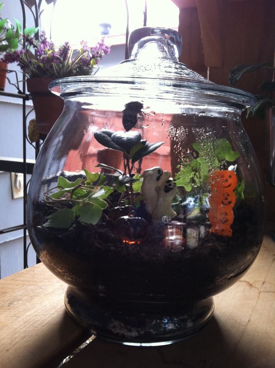 a small and cute Halloween terrarium with greenery, stacked lanterns and ghosts is a lovely idea for your space