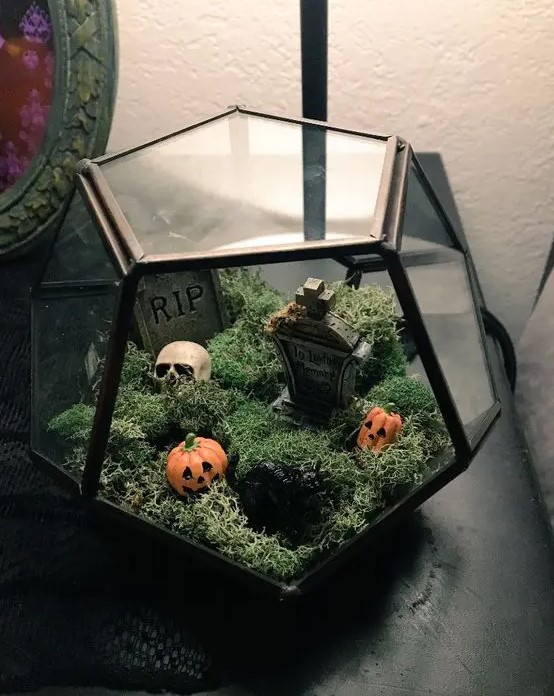 a small and pretty Halloween terrarium with moss, a graveyard and mini jack-o-lanterns is a lovely decor idea