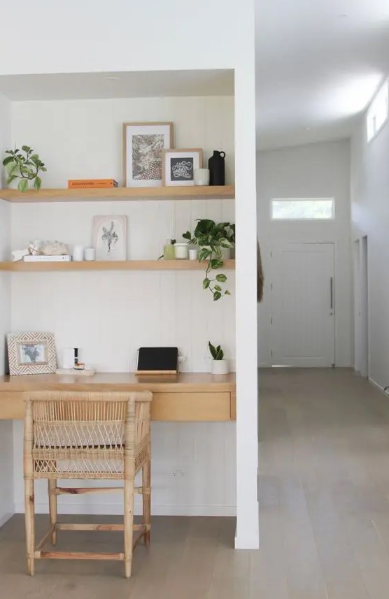 a small niche with white shiplap, built in shelves and a desk with drawers, a rattan chair, some greenery and lovely decor