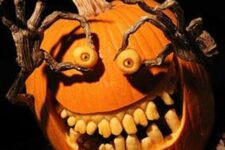 a spooky carved pumpkin with large teeth and monster hands holding the eyes is a bold craft for Halloween