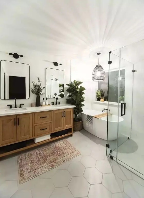 a stylish modern farmhouse bathroom with an oval tub, a double timber vanity, mirrors with black frames, a woven pendant lamp and hex tiles on the floor