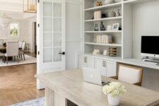 a stylish modern farmhouse home office with built-in cabinets, a neutral desk, a wihte chair and a pendant lamp