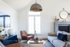 a stylish modern farmhouse living room with a fireplace, a grey sofa, leather chairs, a glossy sideboard and a coffee table