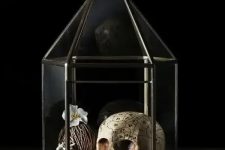 a terrarium with a skull, a black pearl, a faux bloom and driftwood is a beautiful and cool idea for vintage Halloween decor