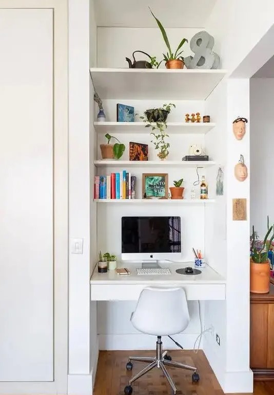 a tiny nook with built in shelves and a desk with a drawer, a white chair, books and potted plants is a cool space fo working