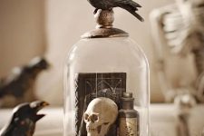 a vintage Halloween cloche with books, a skull, a poison bottle and a blackbird on top is a cool decoration to make yourself