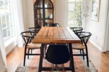 a welcoming rustic dining space with a dining table with a stained tabletop, black woven chairs, a chic chandelier and a vintage buffet